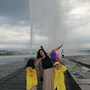 Mujer con sus hijos bajo la lluvia en la fuente del Lago de Ginebra